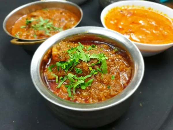 Three house curries presented with rice and naan for sharing.