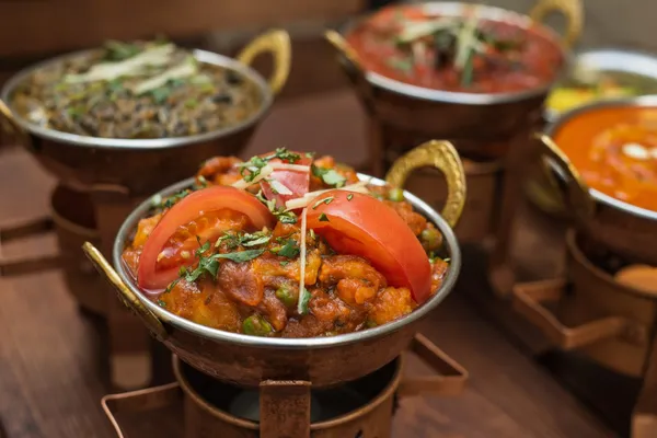Two freshly prepared karahi dishes served side by side with vibrant garnishes.